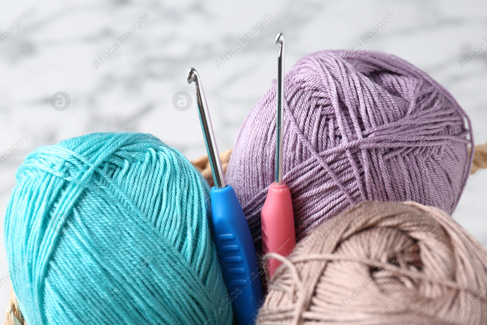 Photo of Crochet hooks and colorful yarns on blurred background, closeup