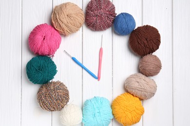 Photo of Clock made of colorful yarns and hooks on white wooden table, flat lay. Time to hobby