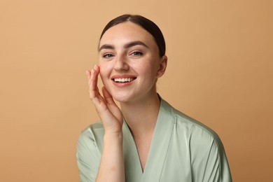 Beautiful young woman with healthy skin on beige background