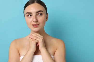 Beautiful young woman with healthy skin on light blue background, space for text