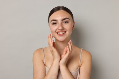 Beautiful young woman with healthy skin on grey background