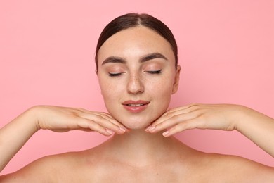Photo of Face massage. Beautiful young woman with healthy skin on pink background