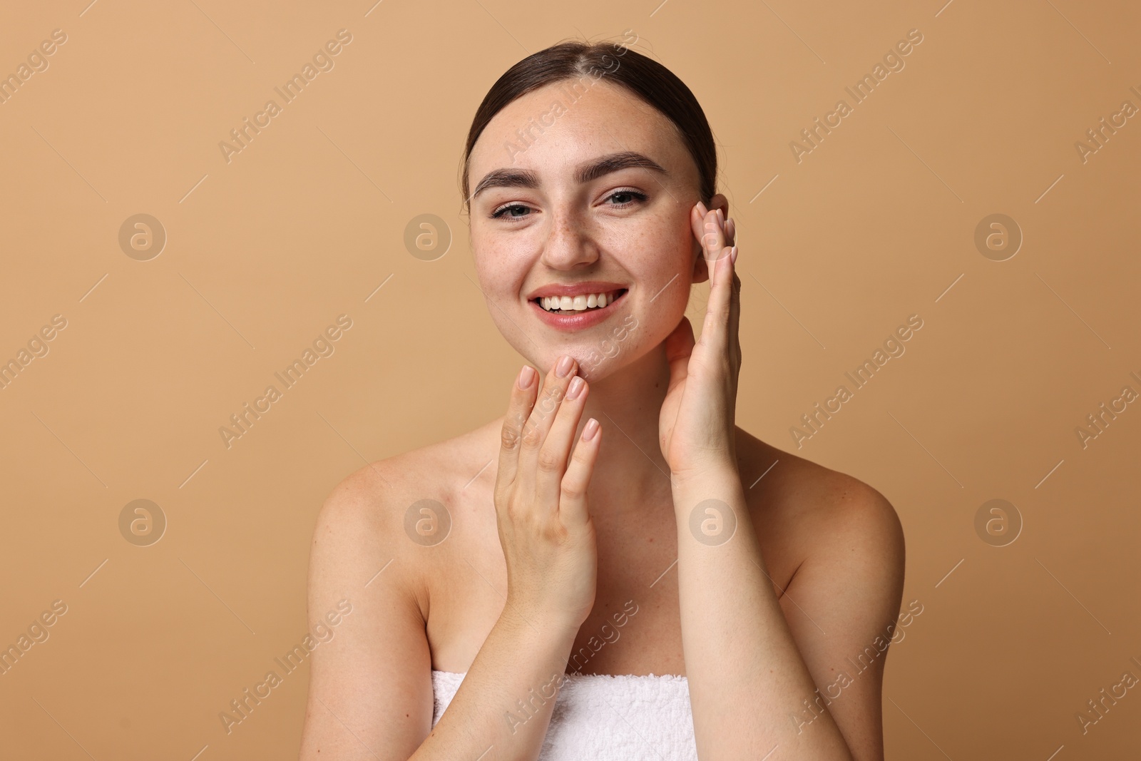 Photo of Face massage. Beautiful young woman with healthy skin on beige background