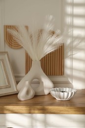 Photo of Beautiful decorative plants, vases, photo frame and ceramic bowl on wooden chest of drawers indoors