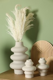 Photo of Beautiful decorative plants, vases and wooden boards on table near green wall indoors