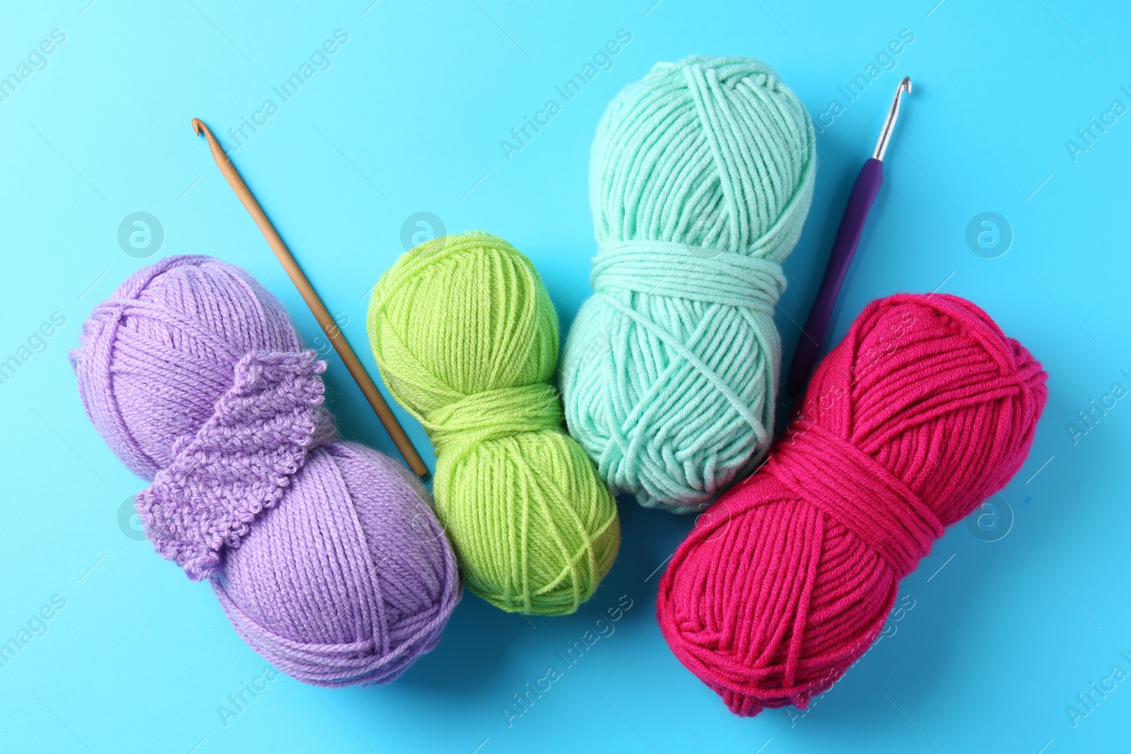 Photo of Colorful yarns, hooks and pattern sample on light blue background, flat lay