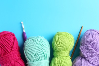 Photo of Colorful yarns, hooks and pattern sample on light blue background, flat lay. Space for text