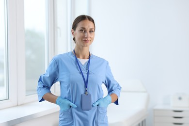 Nurse in medical uniform near window indoors, space for text