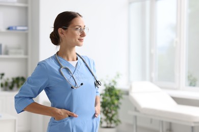 Nurse in medical uniform with stethoscope indoors, space for text