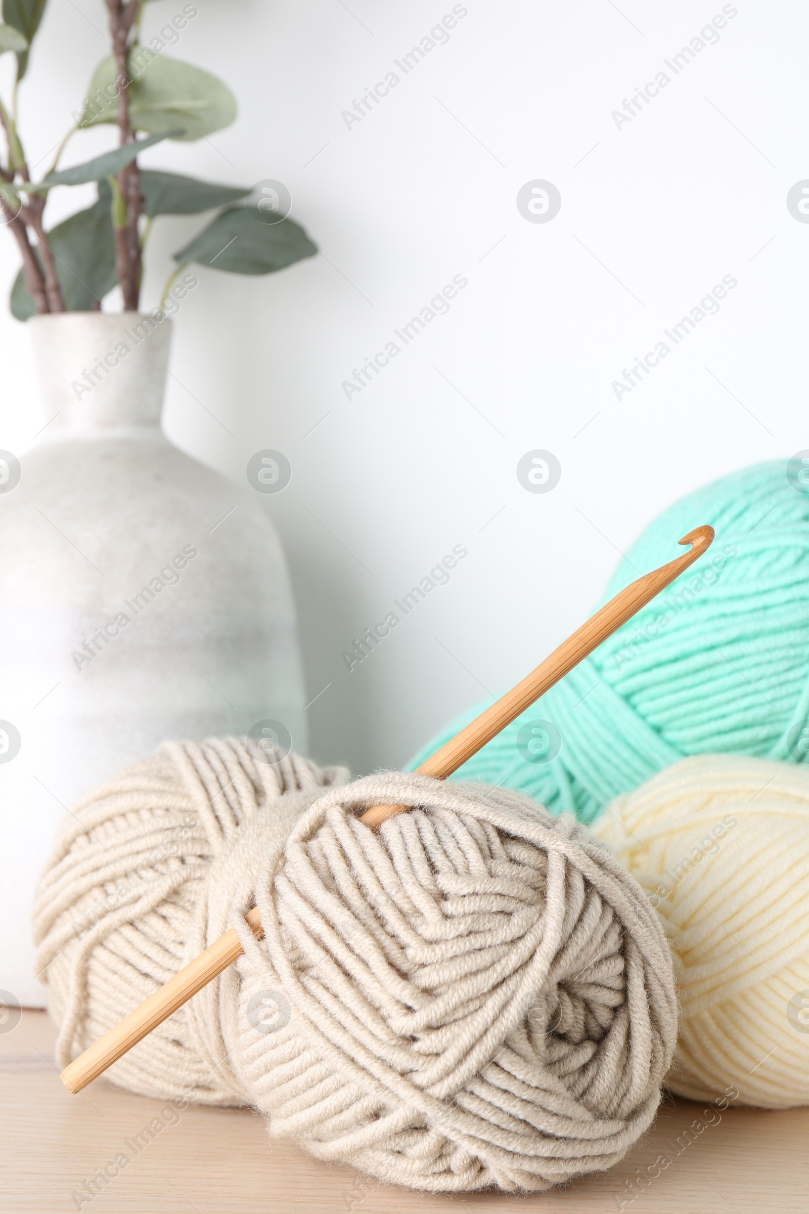 Photo of Skeins of yarn and crochet hook on wooden table, closeup