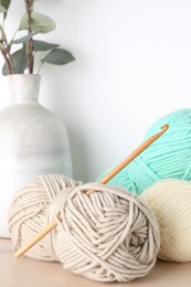 Photo of Skeins of yarn and crochet hook on wooden table, closeup