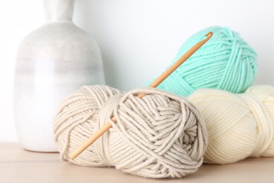 Photo of Skeins of yarn and crochet hook on wooden table, closeup