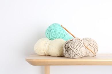 Photo of Skeins of yarn and crochet hook on wooden shelf. Space for text