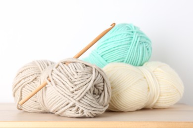 Photo of Skeins of yarn and crochet hook on wooden table, closeup