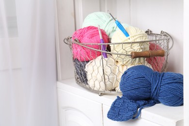 Photo of Different yarns, pattern samples and crochet hooks on white shelf