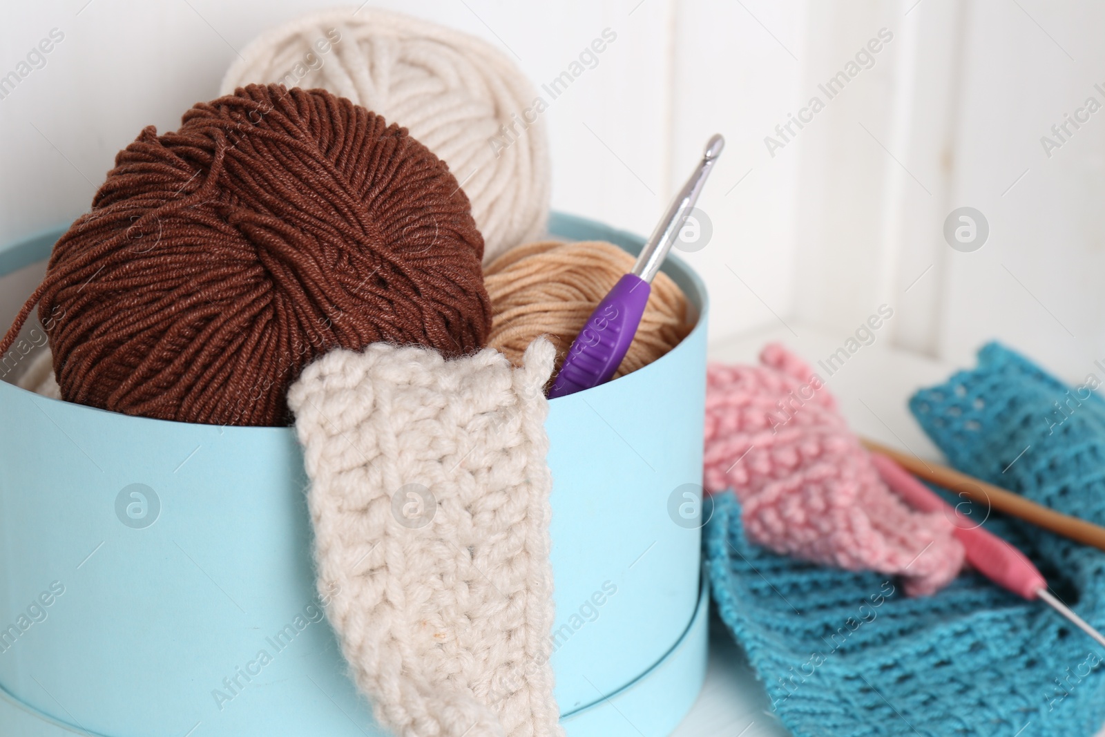 Photo of Different yarns, pattern samples and crochet hooks indoors, closeup