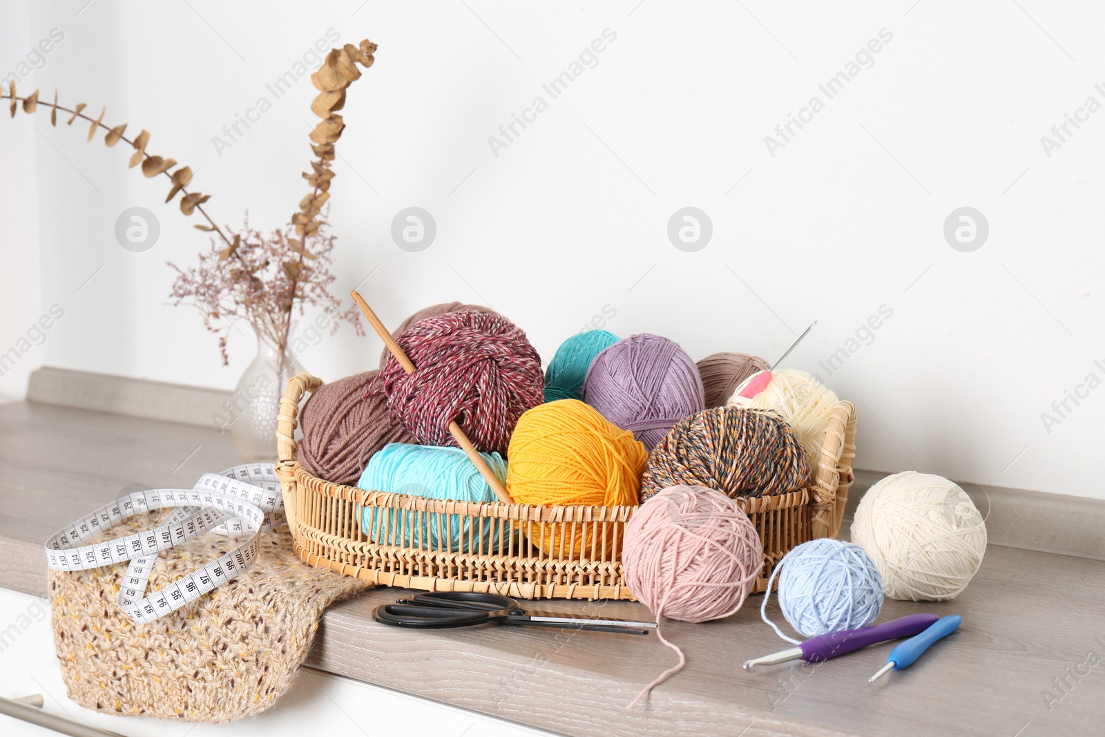 Photo of Different yarns, crochet hooks and other tools on wooden shelf