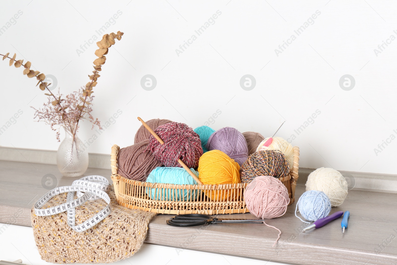 Photo of Different yarns, crochet hooks and other tools on wooden shelf