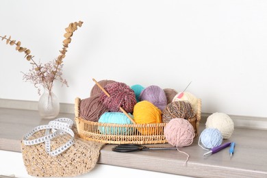 Photo of Different yarns, crochet hooks and other tools on wooden shelf