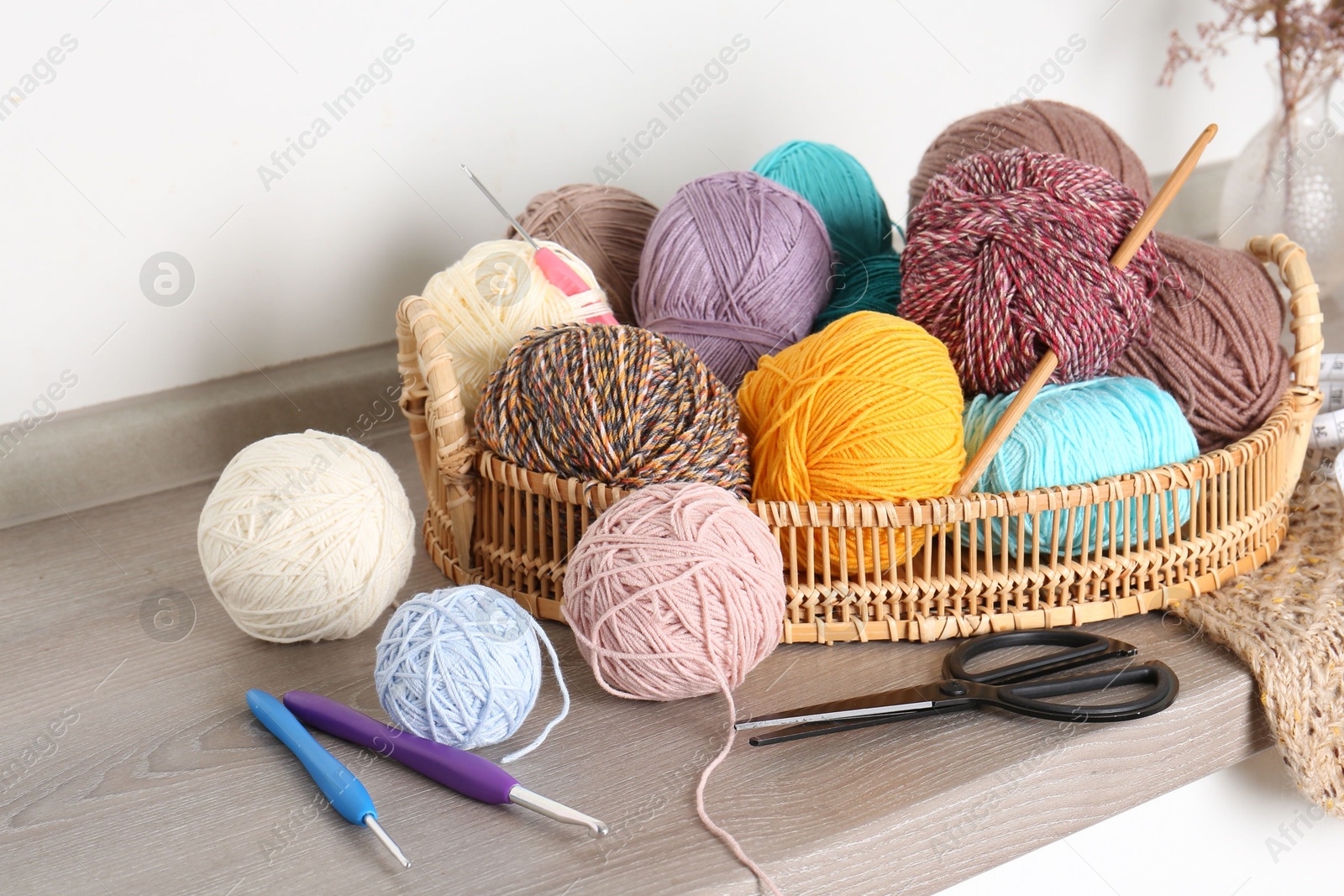 Photo of Different yarns, crochet hooks and other tools on wooden shelf