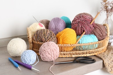 Photo of Different yarns, crochet hooks and other tools on wooden shelf