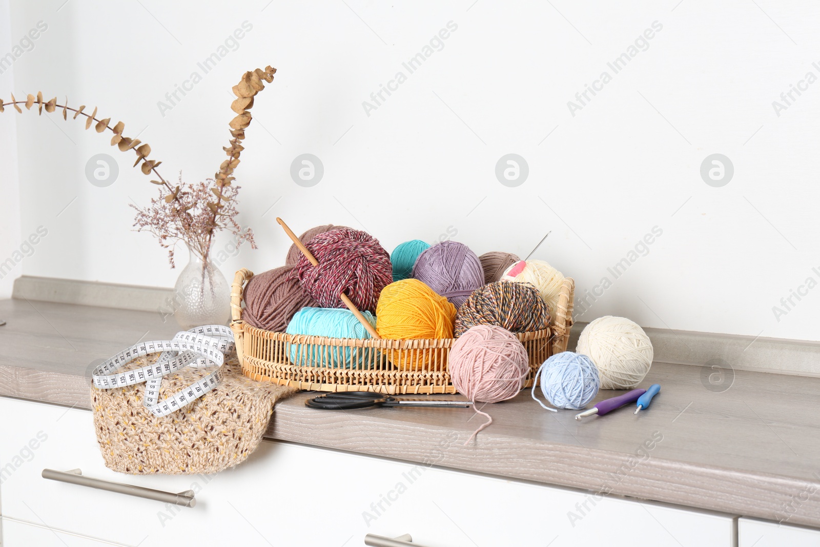 Photo of Different yarns, crochet hooks and other tools on wooden shelf