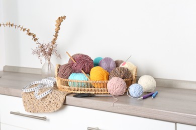 Photo of Different yarns, crochet hooks and other tools on wooden shelf