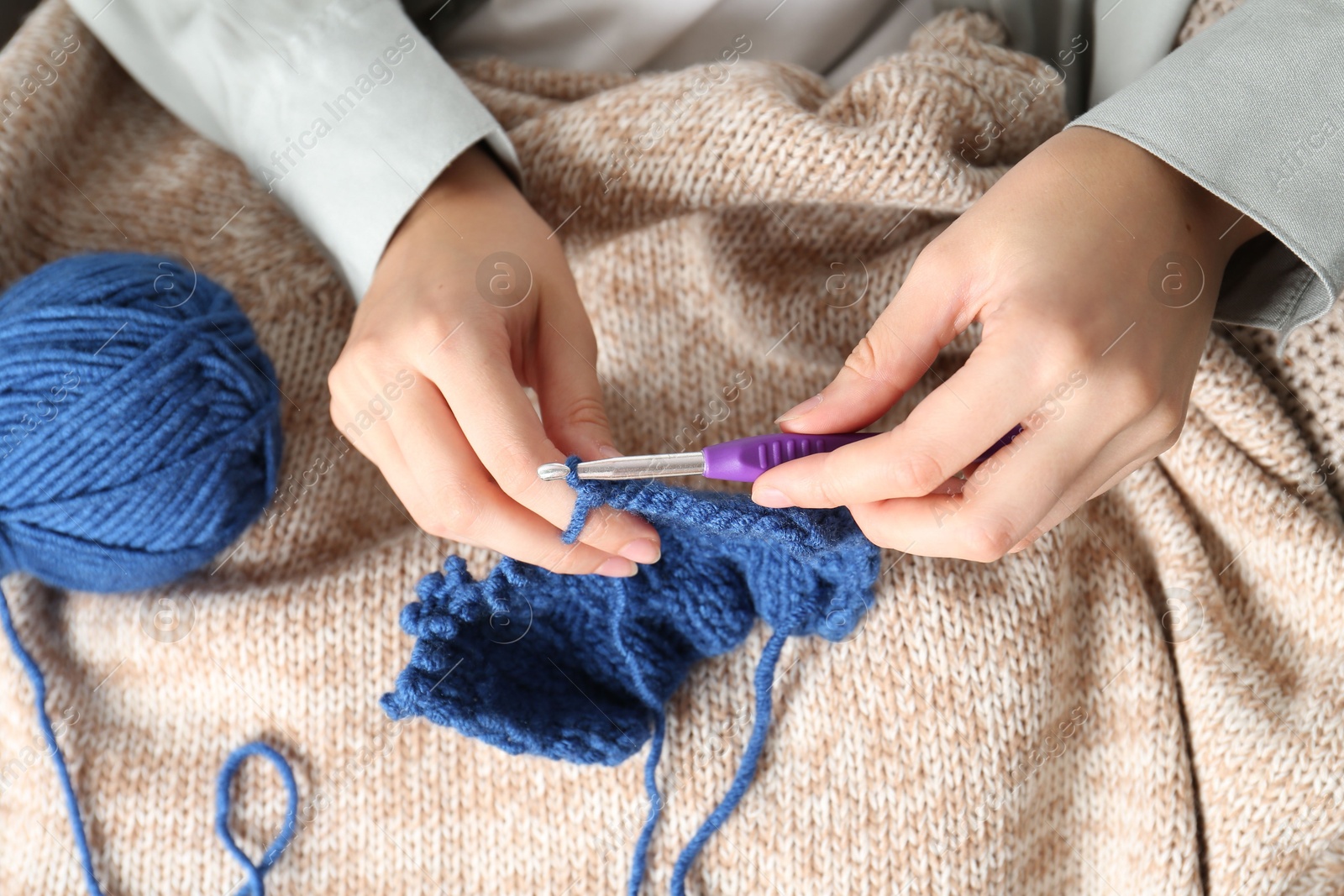 Photo of Woman crocheting with hook and blue yarn, top view