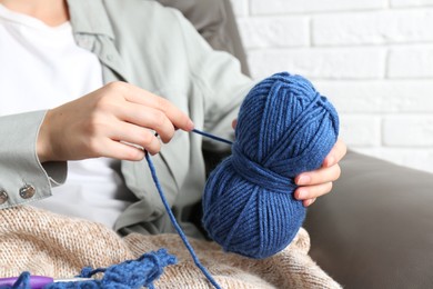 Photo of Woman holding blue yarn at home, closeup