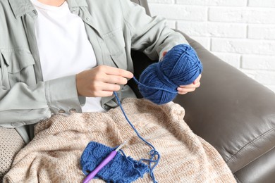 Photo of Woman holding blue yarn at home, closeup