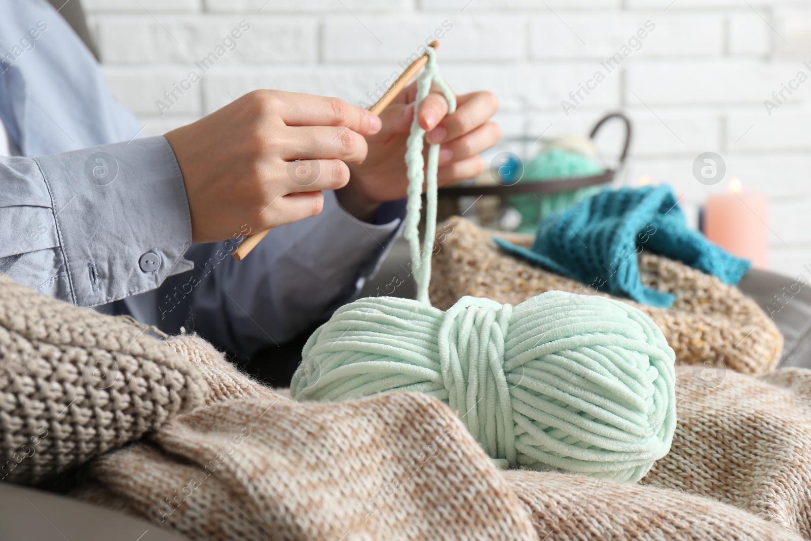 Photo of Woman crocheting with hook and yarn at home, closeup