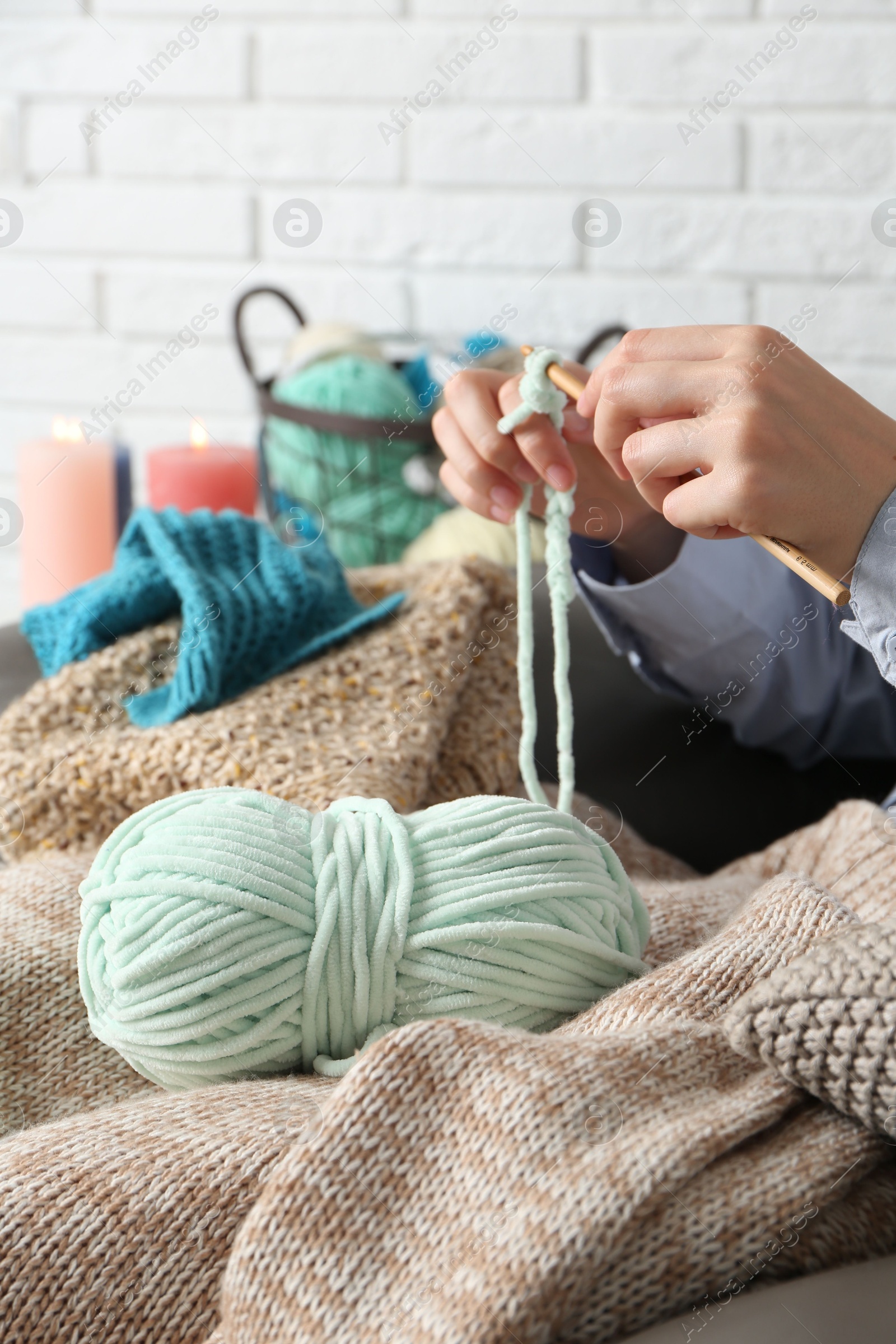 Photo of Woman crocheting with hook and yarn at home, closeup