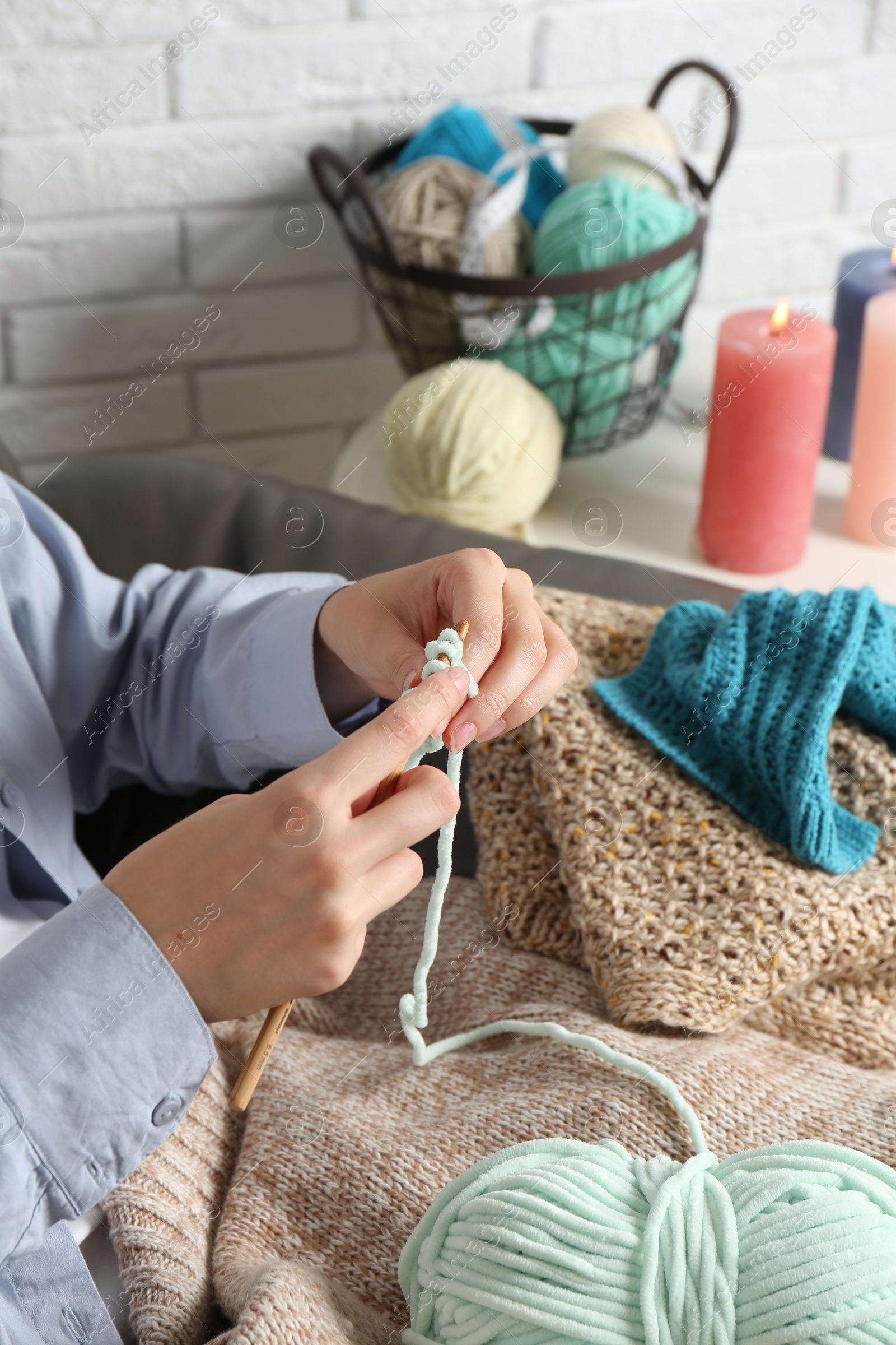 Photo of Woman crocheting with hook and yarn at home, closeup