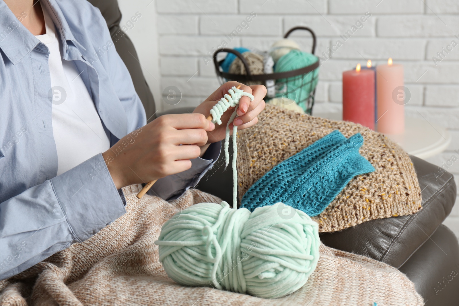 Photo of Woman crocheting with hook and yarn at home, closeup