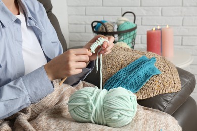 Photo of Woman crocheting with hook and yarn at home, closeup