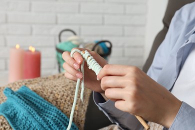 Photo of Woman crocheting with hook and yarn at home, closeup