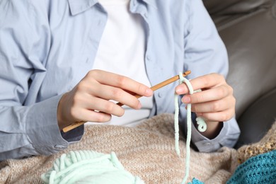 Photo of Woman crocheting with hook and yarn, closeup