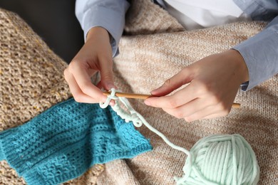 Photo of Woman crocheting with hook and yarn, top view