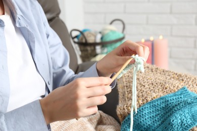 Photo of Woman crocheting with hook and yarn at home, closeup