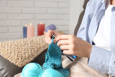 Photo of Woman crocheting with hook and yarn at home, closeup