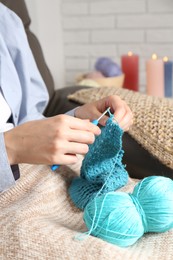 Photo of Woman crocheting with hook and yarn at home, closeup