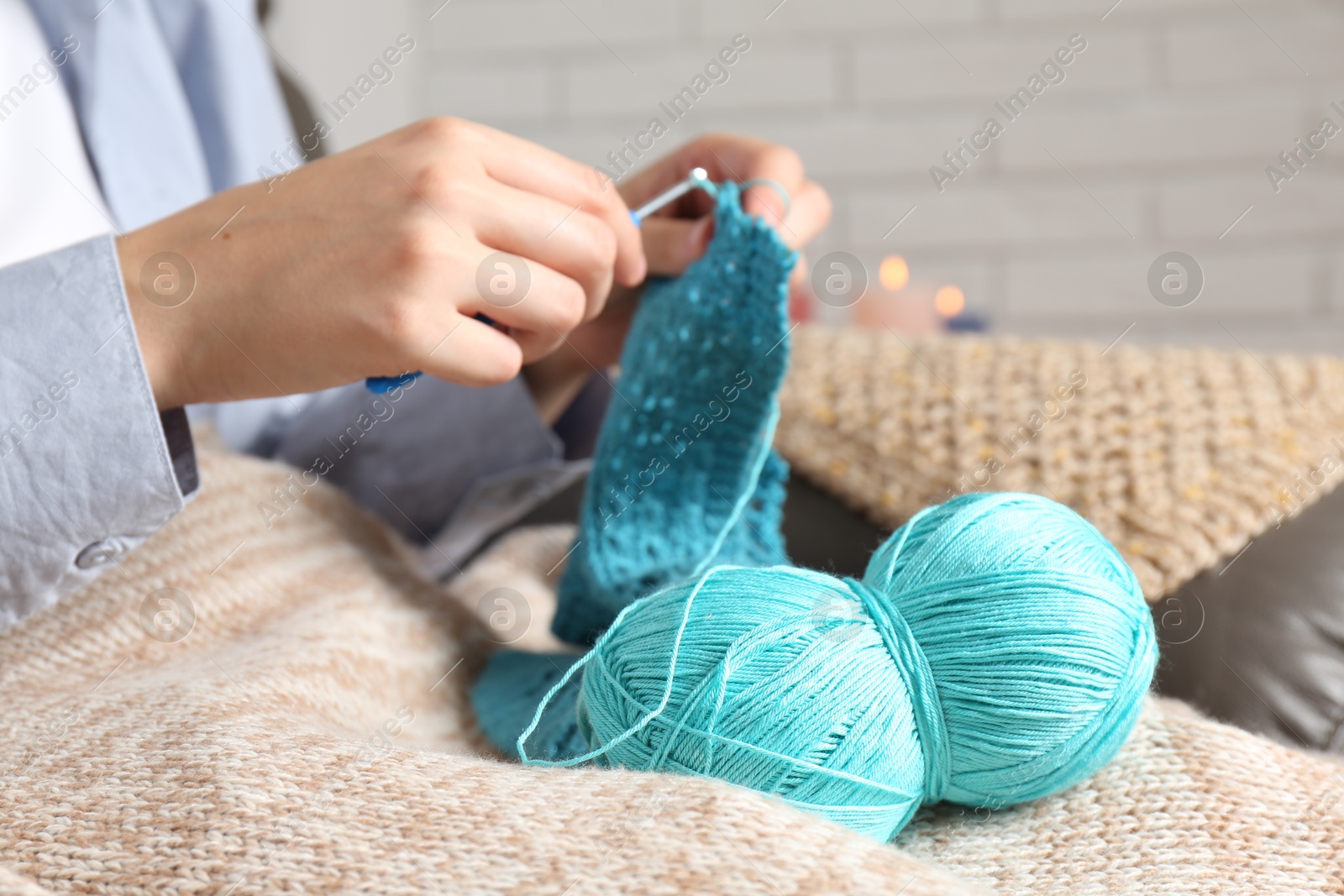 Photo of Woman crocheting with hook and yarn at home, closeup