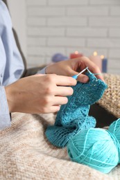 Photo of Woman crocheting with hook and yarn at home, closeup