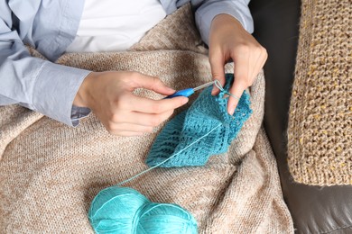 Photo of Woman crocheting with hook and yarn on sofa, above view