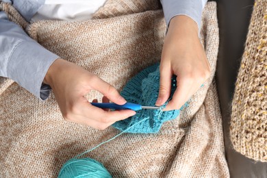 Photo of Woman crocheting with hook and yarn on sofa, above view