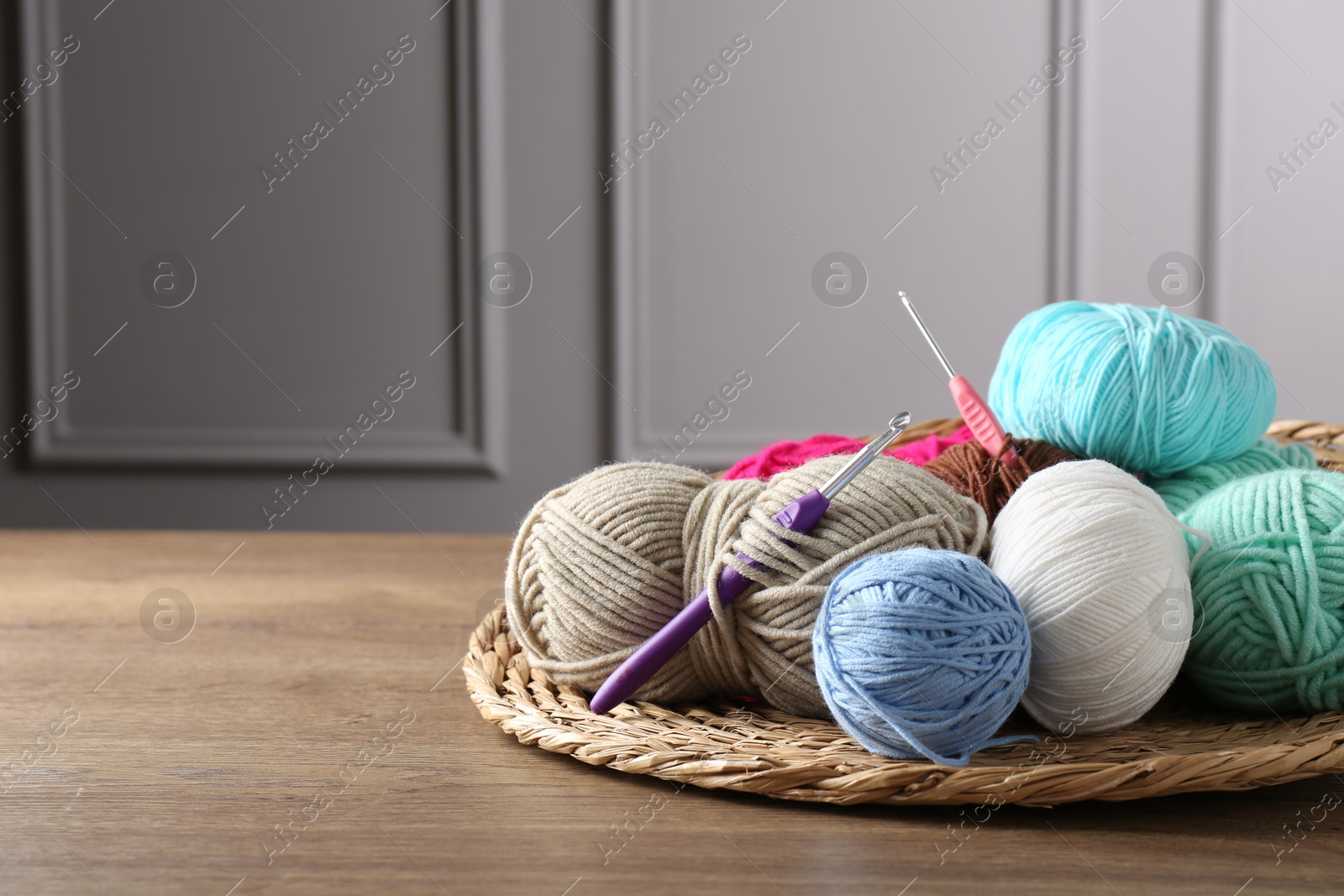 Photo of Different yarns and crochet hooks on wooden table indoors, closeup. Space for text