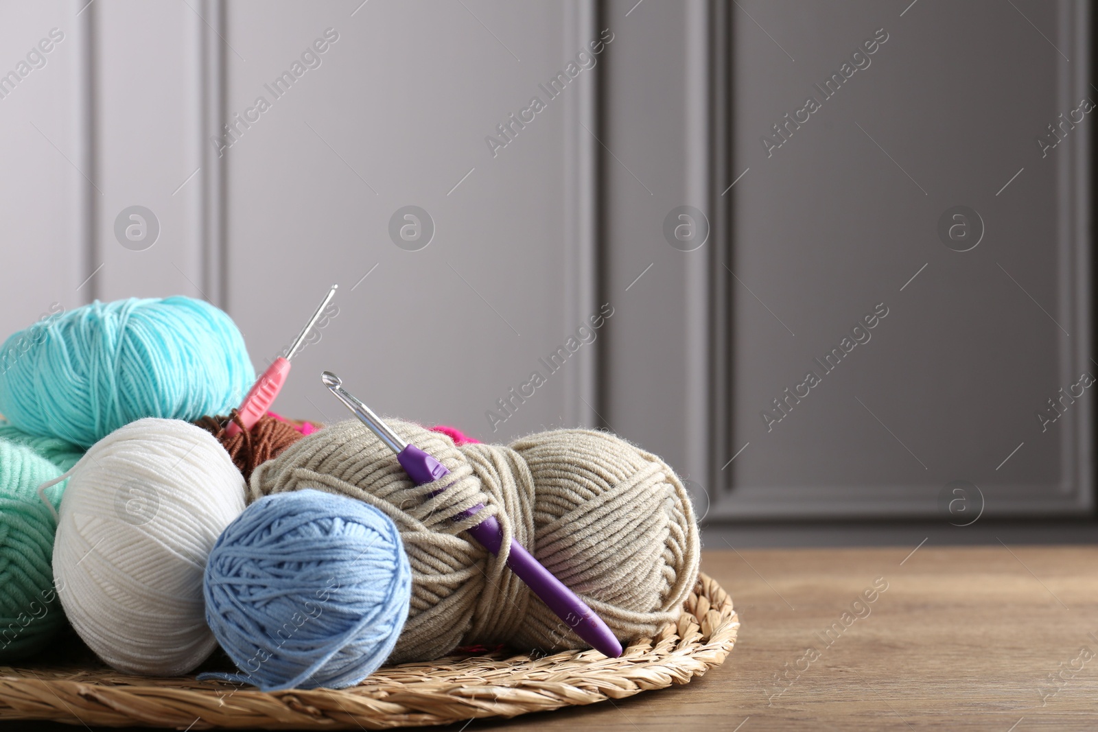 Photo of Different yarns and crochet hooks on wooden table indoors, closeup. Space for text