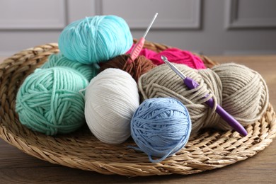 Photo of Different yarns and crochet hooks on wooden table indoors, closeup