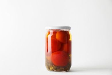 Tasty pickled tomatoes in jar on light grey background