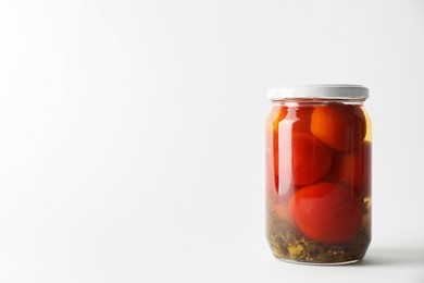 Tasty pickled tomatoes in jar on light grey background. Space for text